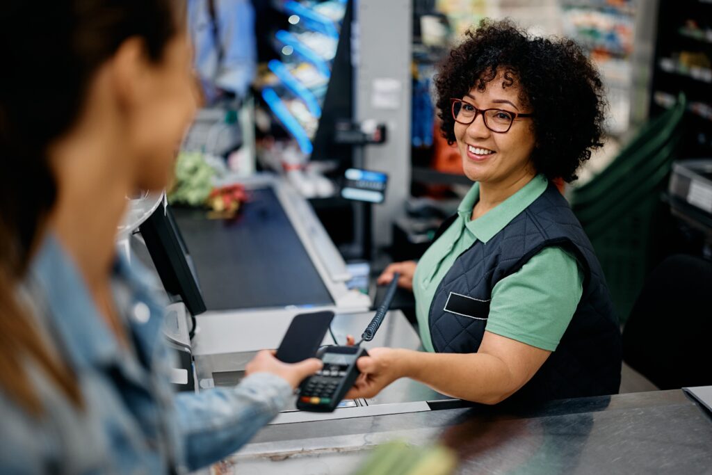 Female grocery store cashier happily interacting with a customer